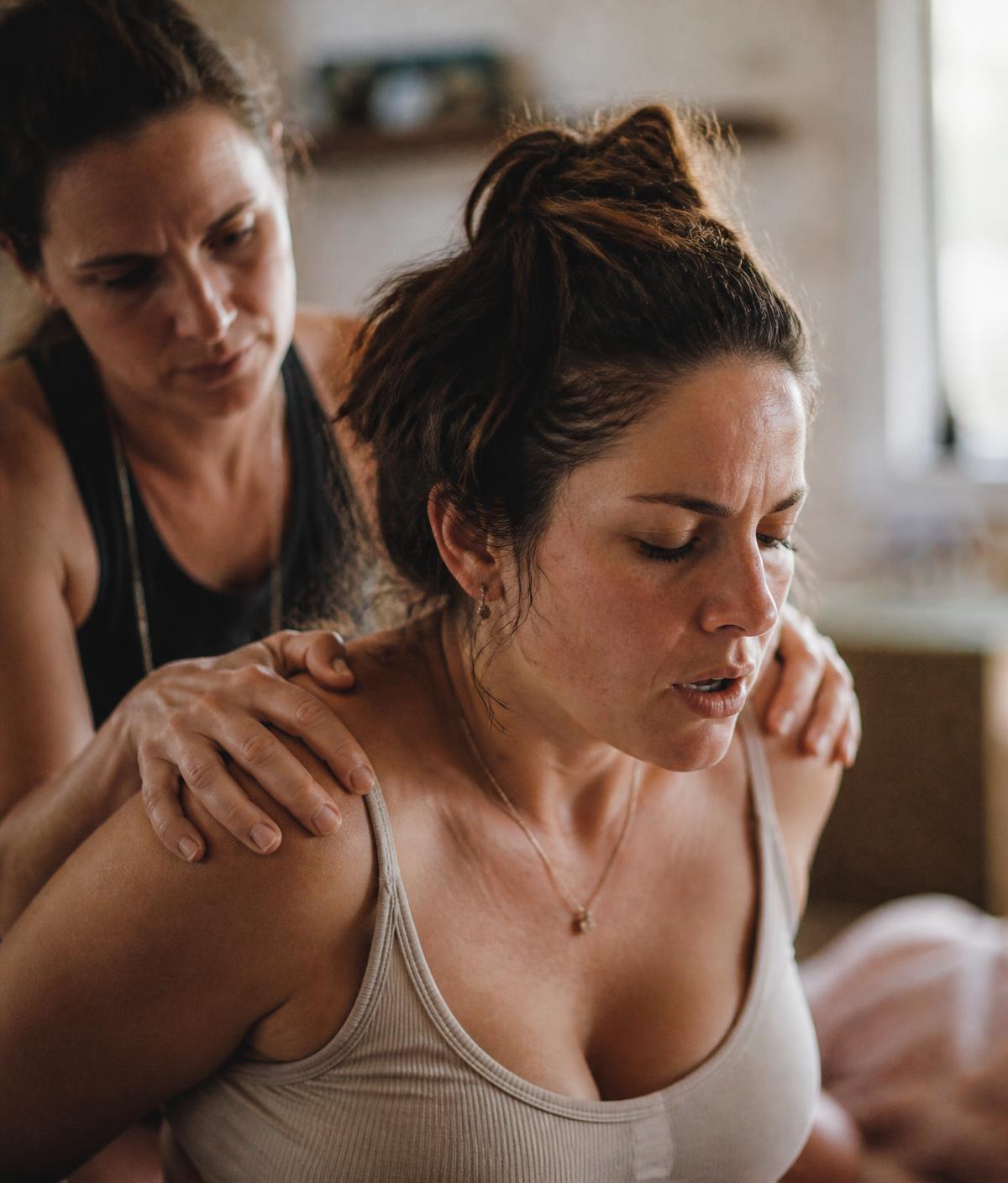 Birth support person steadying a laboring woman's shoulders